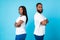 Afro couple standing back to back, blue studio background