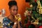 Afro-descendant Colombian woman sitting on the sofa next to the Christmas tree drinking coffee in a cup