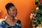 Afro-descendant Colombian woman sitting on the sofa next to the Christmas tree smiling happy