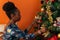 Afro-descendant Colombian woman sitting on the sofa next to the tree decorating it