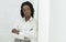 Afro Entrepreneur Lady Standing Next To White Wall Indoor