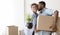 Afro Husband Kissing Wife In Cheek Holding Moving Box Indoor