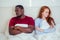 Afro latin american man and redhaired ginger woman ignoring each other after fight on bed in bedroom