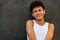 Afro latin male teenager smiling against a wall