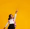 Afro Schoolgirl Pointing Finger Showing Something Over Yellow Background