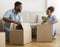 Afro Spouses Packing Boxes Together Sitting On Floor At Home