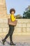 Afro style brunette woman dressed in fashion, walks with a big bag through a city