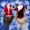 Afroamerican and caucasian-white hands holding phones with 2 Santa Clauses.