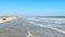 Afternoon beach scene at the ocean with sand, waves, cars, people enjoing.