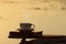 Afternoon coffee cup and book on wooden board with golden light