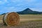 Afternoon in rural Hungary, golden dry bale of hay, mountain peak in background