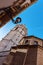 Against background of blue sky, trail from plane, lantern on corner of house and cathedral with bell tower.