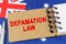 Against the background of the flag of Australia lies a notebook with the inscription - DEFAMATION LAW