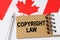 Against the background of the flag of Canada lies a notebook with the inscription - COPYRIGHT LAW