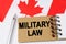 Against the background of the flag of Canada lies a notebook with the inscription - MILITARY LAW