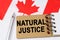 Against the background of the flag of Canada lies a notebook with the inscription - NATURAL JUSTICE