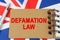 Against the background of the flag of Great Britain lies a notebook with the inscription - DEFAMATION LAW