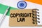 Against the background of the flag of India lies a notebook with the inscription - COPYRIGHT LAW