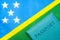 Against the background of the flag of the Solomon Islands is a passport