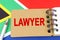 Against the background of the flag of South Africa lies a notebook with the inscription - LAWYER