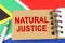 Against the background of the flag of South Africa lies a notebook with the inscription - NATURAL JUSTICE