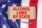Against the background of the flag of the USA lies a notebook with the inscription - ALCOHOL LAWS BY STATE