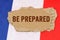 Against the background of the French flag lies cardboard with the inscription - Be Prepared