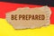 Against the background of the German flag lies cardboard with the inscription - Be Prepared