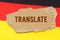 Against the background of the German flag lies cardboard with the inscription - Translate