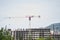 Against the background of a high-rise building under construction, tall tower cranes stood against the sky and mountains