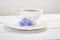 Against the background of a mug with an invigorating drink. Cichorium flowers in a saucer. Flowers of ordinary chicory