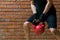 Against a background of orange brick, a man in black uniform, plays sports, lifts a large red weight, close-up, there is a place