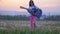 Against background of the urban landscape funny little girl musician on sunglasses playing the guitar and walks in meadow of dande