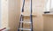 Against the background of wooden walls, a ladder for working at height and a piece of ceiling lining