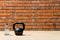 Against a brick wall, close-up of a black sports kettlebell and a bottle of water, there is a place for inscription