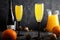 Against a dark background, two glasses with a Mimosa Cocktail. Champagne with orange juice. Festive drink