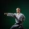 Against dark green background the athlete trains formal karate exercises