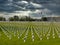 Against dark, threatening skies, rows of graves of WW1 soldiers marked by white crosses in La Targette cemetery in France