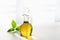 Against the window, olive oil in a decanter on a white background with a green leaf