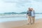 Age, Travel, Tourism and people concept - happy senior couple holding hands and walking on summer beach