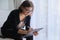 Age woman social worker, psychologist sitting near the window with clipping board