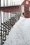 Aged agricultural red traditional barn on idyllic rural farmland, ranch road with snow and rustic old wooden fence