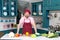 Aged bearded Chef in red apron and red cap standing at kitchen t