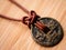 Aged China Coin on Brown Leather Cord Macro Wood Background