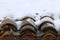 Aged clay roof tiles snowed under winter snow