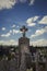 Aged cross tomb stone at cemetery with cloudy sky. Old tombstone in a graveyard