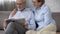 Aged husband reading newspaper, wife hugging him with love, harmonious couple