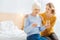 Aged ill woman sitting with pills while her granddaughter supporting her