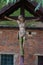 aged Jesus crucified statue against green red roof wall