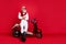 Aged macho man sitting on retro moped with crossed arms wear jumper and trousers isolated red background